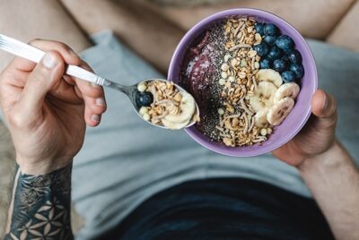 Image of a tattooed person holding a healthy breakfast bowl
