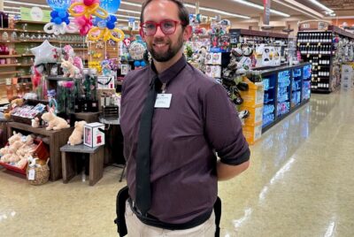 A man in a tie stands in a store aisle